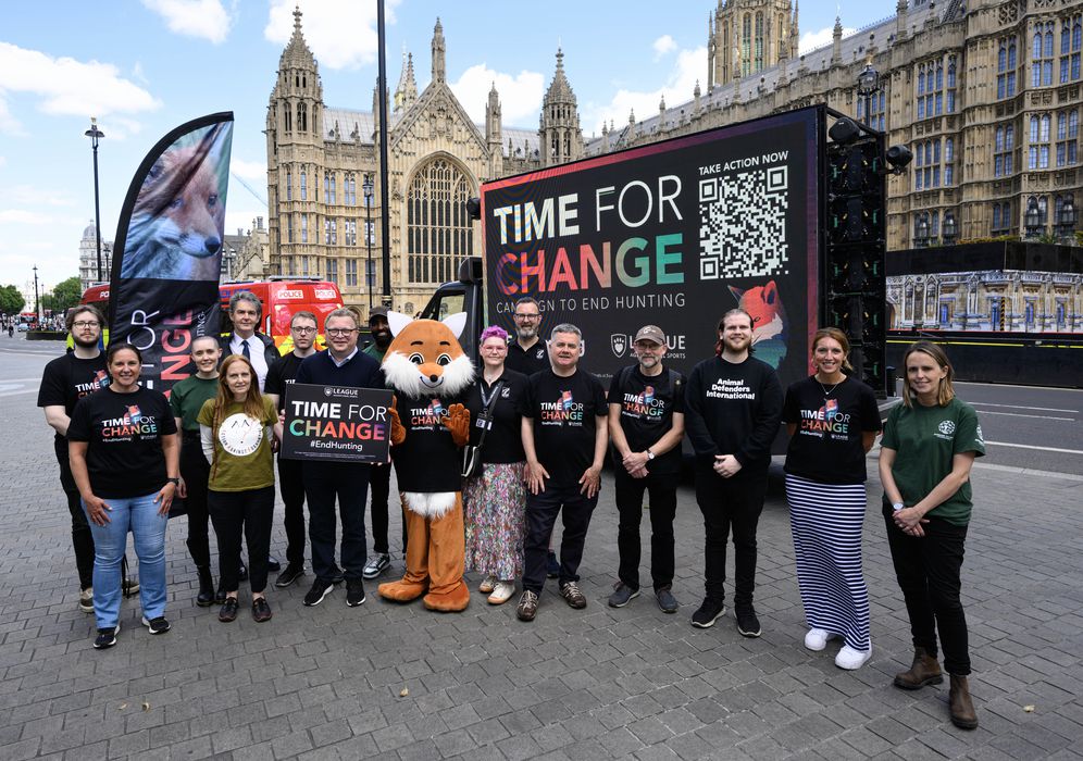 a group of people standing outside the houses of parliament