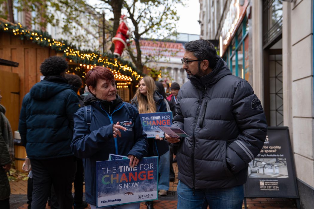 A campaigner with short hair speaks to a tall man wearing a coat